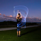 Person performing light painting with a blue and white light effect at night.