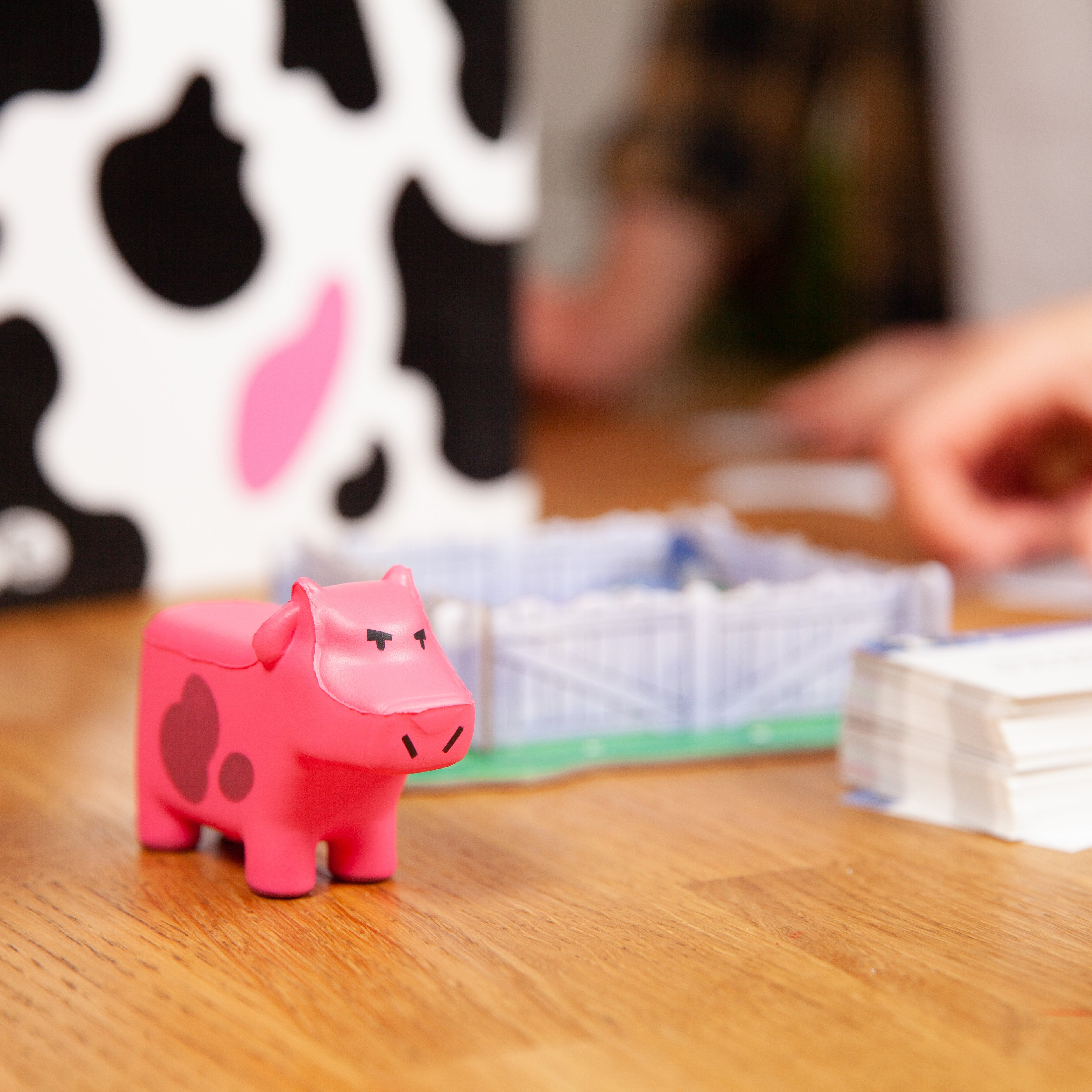 Pink cow-shaped figurine on a wooden table with game components in the background